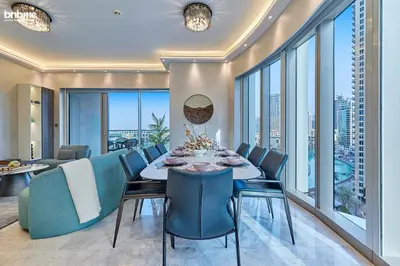a dining room with a table and chairs and windows at bnbme - Luxury Downtown Dubai Apt Burj Khalifa Fountain Views Pool Gym Parking in Dubai