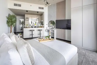 a bedroom with a large white bed and a kitchen at Frank Porter - Al Jawhara Tower in Dubai