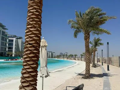 a beach with two palm trees and an umbrella at Stunning Central 2BR Lagoon View & Private Beach in Dubai