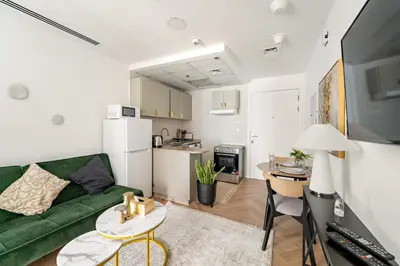 a living room with a green couch and a kitchen at Bright Studio in Dubai Gate 2 in Dubai