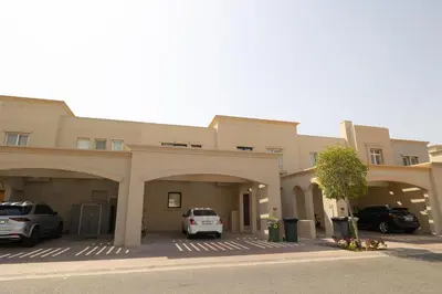 a building with two cars parked in a parking lot at Designer Furnished Villa with Luxury Finishes in Springs 14 in Dubai