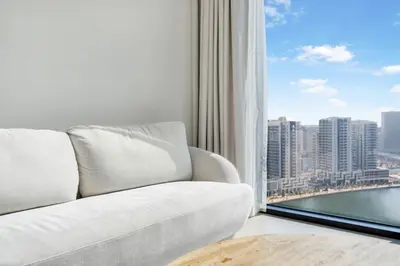 a living room with a white couch and a large window at FAM Living Trillionaire Residences Premium Studio with Private Jacuzzi and Canal View in Dubai