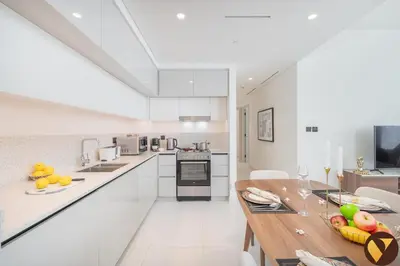 a kitchen with white cabinets and a wooden table at Vogue Emaar Beach Front Marina Vista near JBR and Palm Jumeirah, Two Bedroom Apartment with Balcony and Private Beach, Access to all Amenities in Dubai