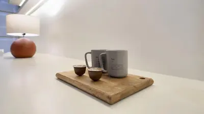 a coffee maker and two cups on a cutting board at New Modern Japanese Style Studio by Downtown in Dubai