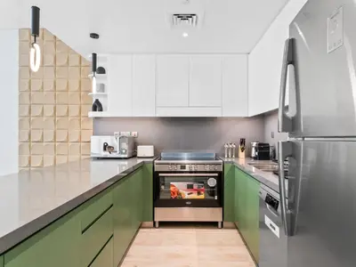 a kitchen with green cabinets and a stainless steel refrigerator at Modern Serenity Central Park 2BR Escape-51 in Dubai