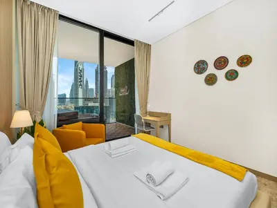 a bedroom with a large white bed and a yellow chair at Premium Burj Khalifa View & Private Jacuzzi in Dubai