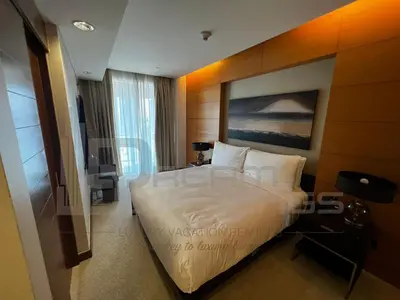 a bedroom with a large white bed and a television at Kempinski Central Avenue One Bedroom in Dubai