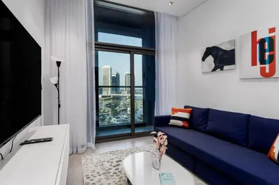 a living room with a blue couch and a large window at Waves - Premium 1BR Apartment Overlooking Burj Khalifa in Dubai