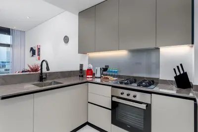 a kitchen with white cabinets and a stove top oven at Waves - Premium 1BR Apartment Overlooking Burj Khalifa in Dubai