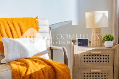 a bed with an orange blanket next to a nightstand at Bloomfields Cozy Stu in Alexis Tower in Dubai