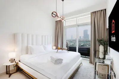 a bedroom with a white bed and a large window at Livbnb - Chic 1BR, Beachfront & Marina Views in Dubai
