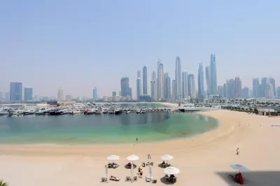 a beach with umbrellas and boats in the water at Livbnb - Chic 1BR, Beachfront & Marina Views in Dubai