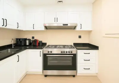 a kitchen with a stove and white cabinets at DreamShoma- Super Spacious 1BR Lake View in Dubai