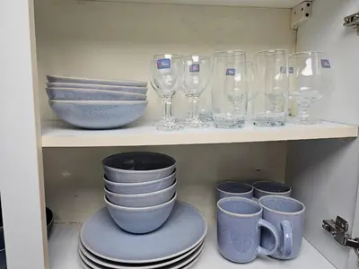 a shelf with plates and glasses and bowls and cups at Diamond Marina Inn, Heart of Marina in Dubai