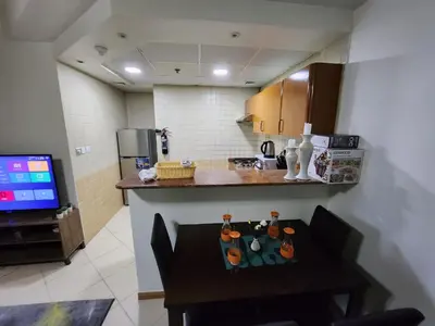 a kitchen with a table and a television in a room at Diamond Marina Inn, Heart of Marina in Dubai