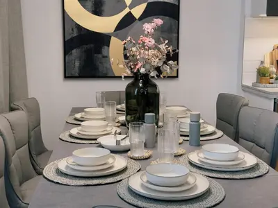 a dining room table with plates and a vase of flowers at Elite Turnkey Residence 2BR in OIA Motor City 237 Dubai in Dubai