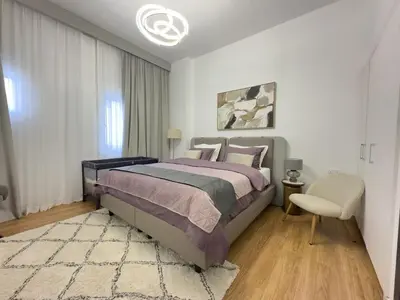 a bedroom with a large bed and a chair at Elite Turnkey Residence 2BR in OIA Motor City 237 Dubai in Dubai