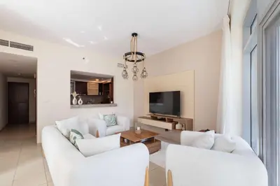 a living room with two white couches and a tv at Beautiful Marina Views 1 Bed in Dubai