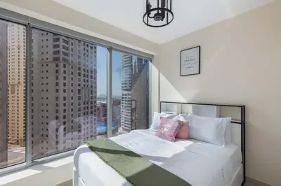 a bedroom with a white bed with a large window at Beautiful Marina Views 1 Bed in Dubai