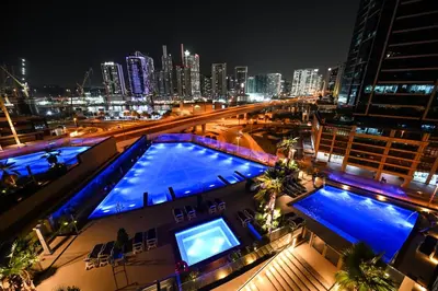 a view of a city at night with a swimming pool at Spacious 1 BHK with City Views Near Burj Khalifa in Dubai