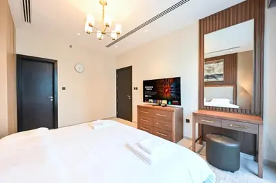 a bedroom with a bed and a tv and a mirror at Spacious 1 BHK with City Views Near Burj Khalifa in Dubai