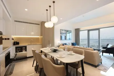 a dining room and living room with a table and chairs at Livbnb - Premium 3BR with Burj Skyline View in Dubai