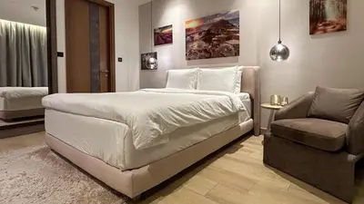 a bedroom with a large white bed and a chair at Bespoke Holiday Homes - Cozy 1BR Retreat in Haven Residences JVC in Dubai