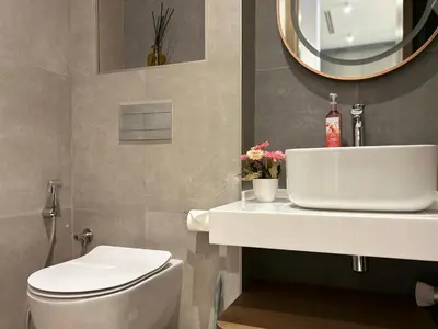 a bathroom with a sink and a toilet and a mirror at Bespoke Holiday Homes - Cozy 1BR Retreat in Haven Residences JVC in Dubai