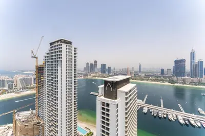 a tall white building next to a river with a bridge at Upscale 2-BR with Sea View - Grand Bleu by Elie Saab in Dubai