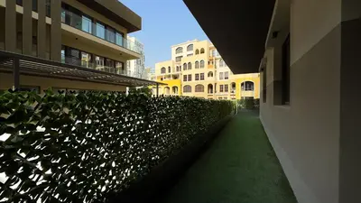 a hallway of a building with a hedge with white flowers at Joya Verde Residence - 1BHK Huge Apartment in Dubai