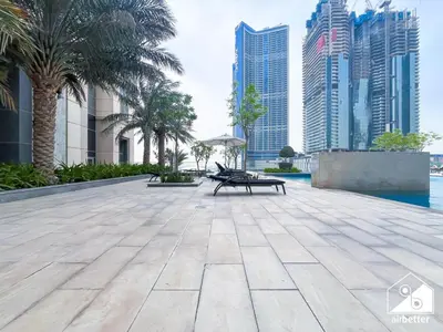 a patio with a bench and palm trees and buildings at Stunning 2-Bedroom Apartment with Canal Views in Dubai