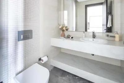 a white bathroom with a toilet and a sink at Frank Porter - Nobles Tower in Dubai
