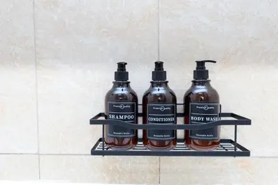 three bottles of alcohol sit on a shelf in a bathroom at Serene studio apartment with Burj Khalifa view in Jumairah Village Circle JVC in Dubai