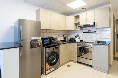 a kitchen with a refrigerator and a washer and dryer at Serene studio apartment with Burj Khalifa view in Jumairah Village Circle JVC in Dubai