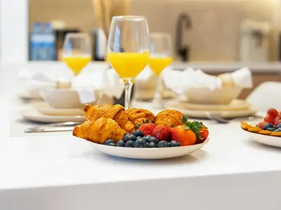 a table with a plate of food and glasses of orange juice at Brand New Luxurious 2 Bed in JVC with Padel Court in Dubai