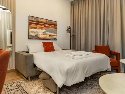 a hotel room with a bed and a chair at Brand New Luxury 2 Bedroom with Padel Gym Pool Cinema in Dubai
