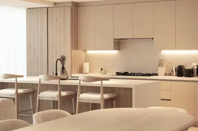 a kitchen with white cabinets and bar stools at Seraya Residences at Marquise Square Tower in Dubai