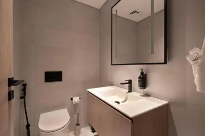 a bathroom with a sink and a toilet and a mirror at Seraya Residences at Marquise Square Tower in Dubai