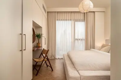 a bedroom with a bed and a chair and a window at Seraya Residence 3 - 4BDR - Burj Views - Amenities and Concierge in Dubai