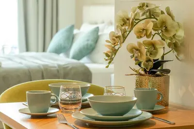 a table with plates and cups and a vase with flowers at Sea-View Studio at Seven Palm in Dubai