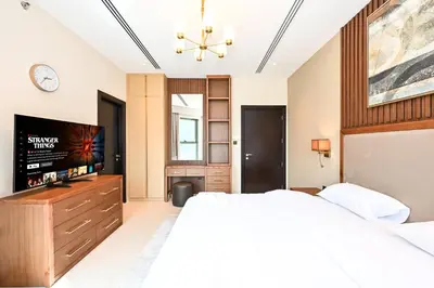 a bedroom with a large bed and a flat screen tv at Cozy & Spacious 2 BHK Downtown in Dubai