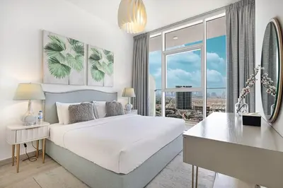 a bedroom with a bed with a desk and a large window at Luxury One-Bedroom Apartment in Bloom Heights in Dubai