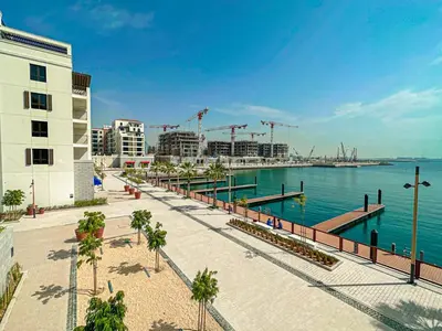a walkway next to a body of water with buildings at HiGuests - Breezy 1 BR Retreat Near La Mer Beach in Dubai