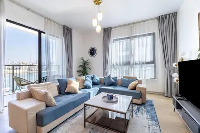 a living room with a blue couch and large windows at Goldbest Beachfront 2BR La Mer in Dubai