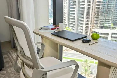 a desk with a laptop and chairs in a room with a window at Majestic Act2 1BR Dowtown Dubai in Dubai