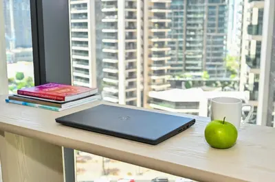 a laptop on a desk with a cup and a green apple at Majestic Act2 1BR Dowtown Dubai in Dubai
