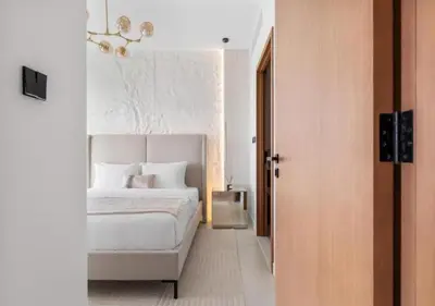 a bedroom with a white bed and a chandelier at Novity Signature Homes in Dubai