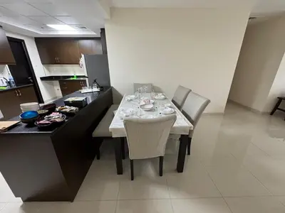 a kitchen with a table with chairs and a dining room at Stylish 2BHK in Prime Location in Dubai