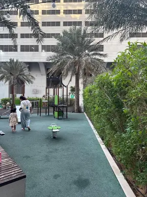 a woman walking down a walkway with palm trees at Stylish 2BHK in Prime Location in Dubai