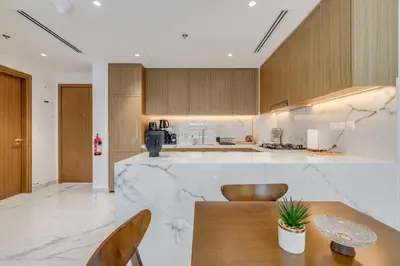 a kitchen with a marble counter top and wooden cabinets at GLOBALSTAY Azizi Riviera 59 in Dubai
